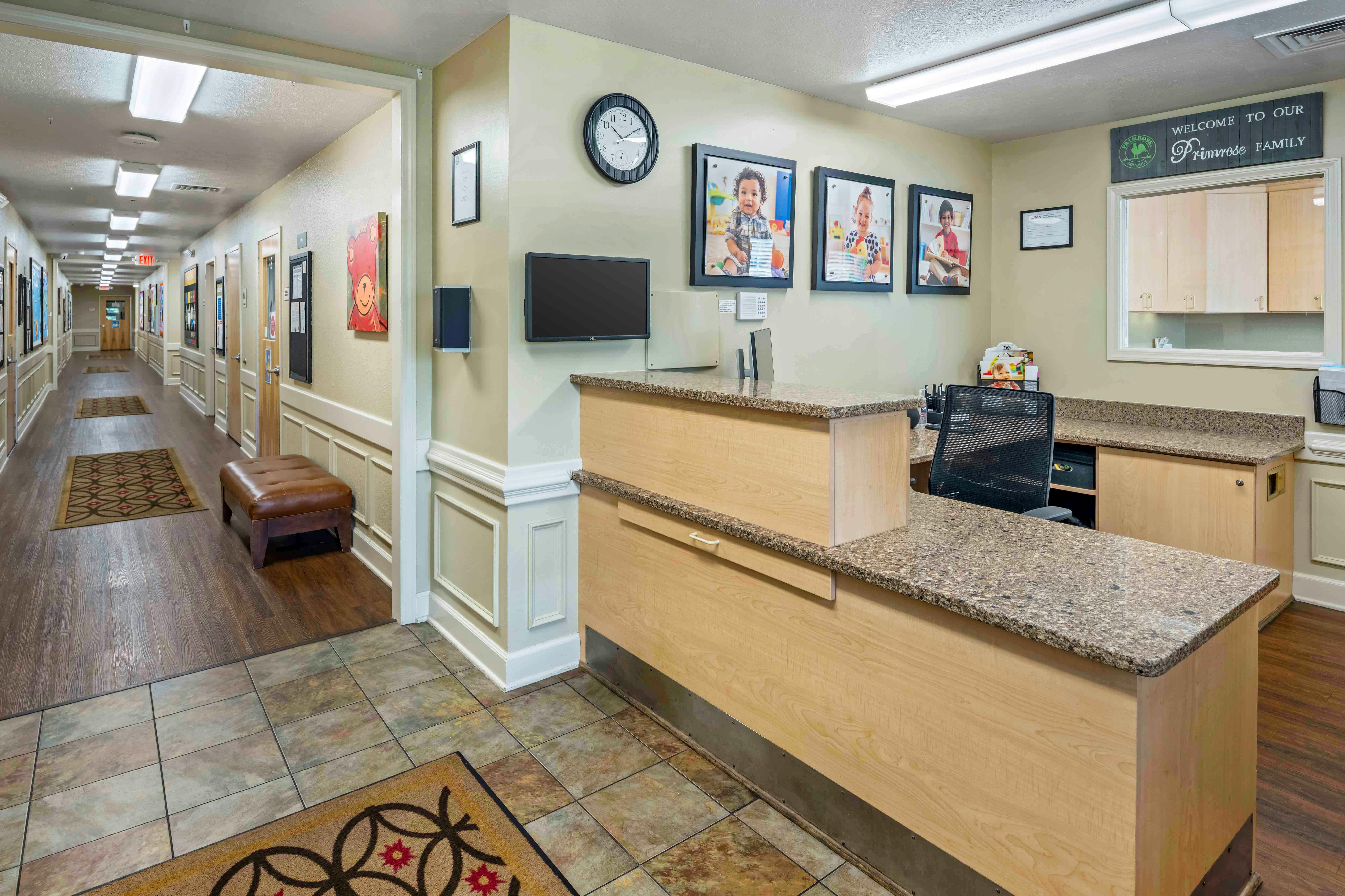 Reception area of a school with a desk, hallway, and photos of children