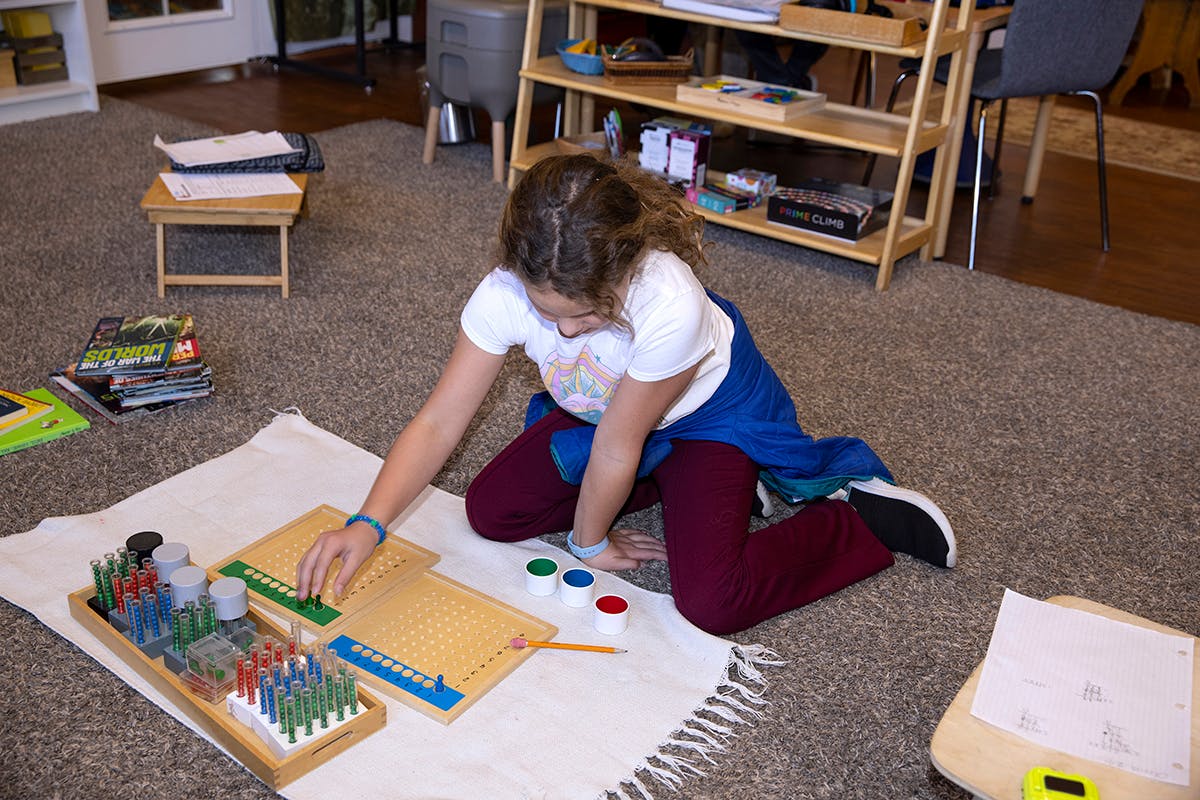Child kneeling on floor, working with wooden learning materials
