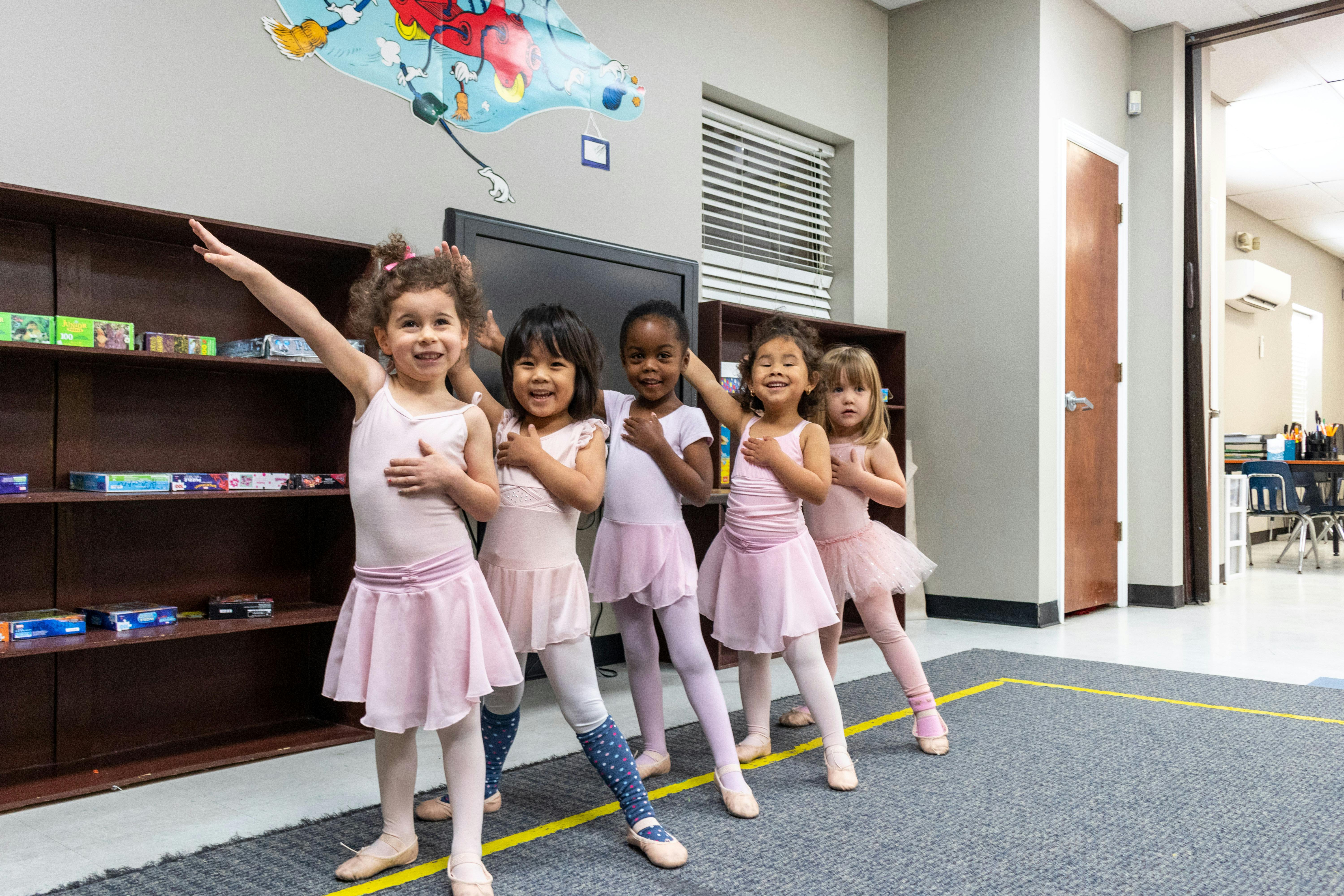 Five children in ballet attire posing in a line