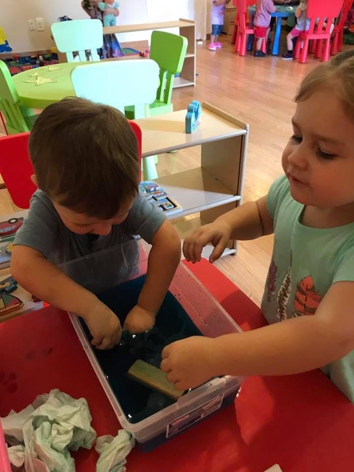 Two children playing with water in a container