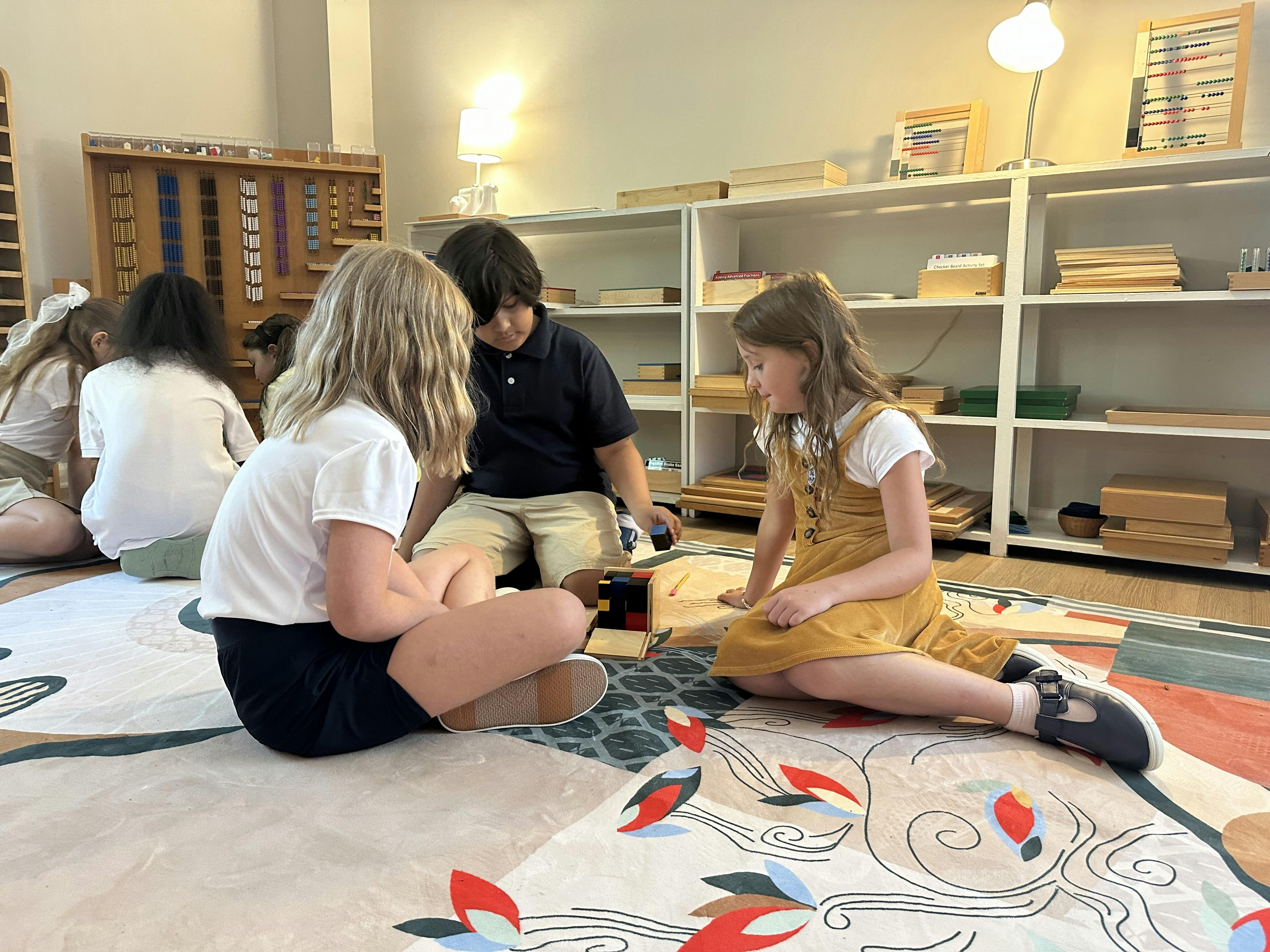 Three children sitting on the floor with building blocks