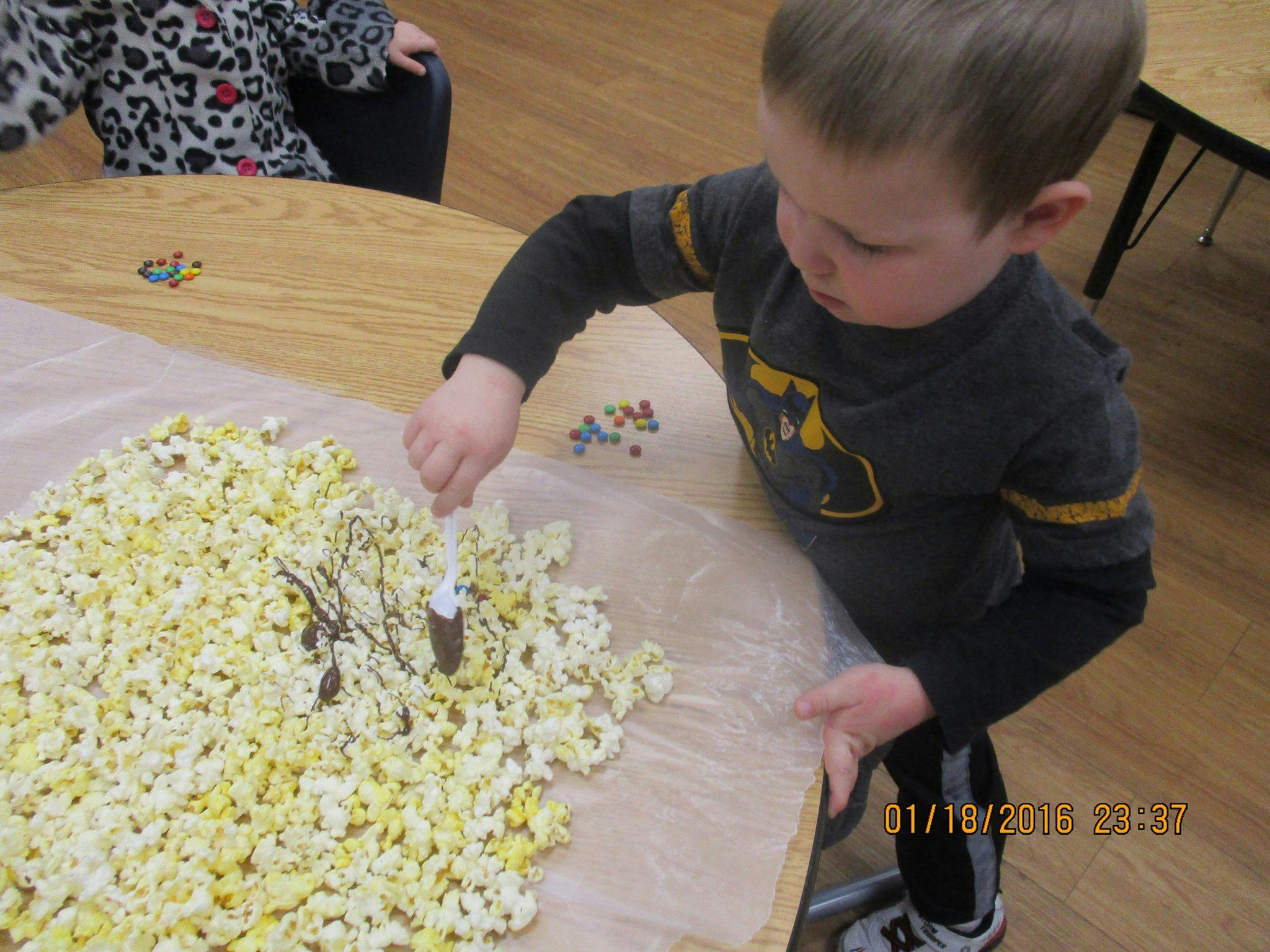 Child decorating popcorn with chocolate