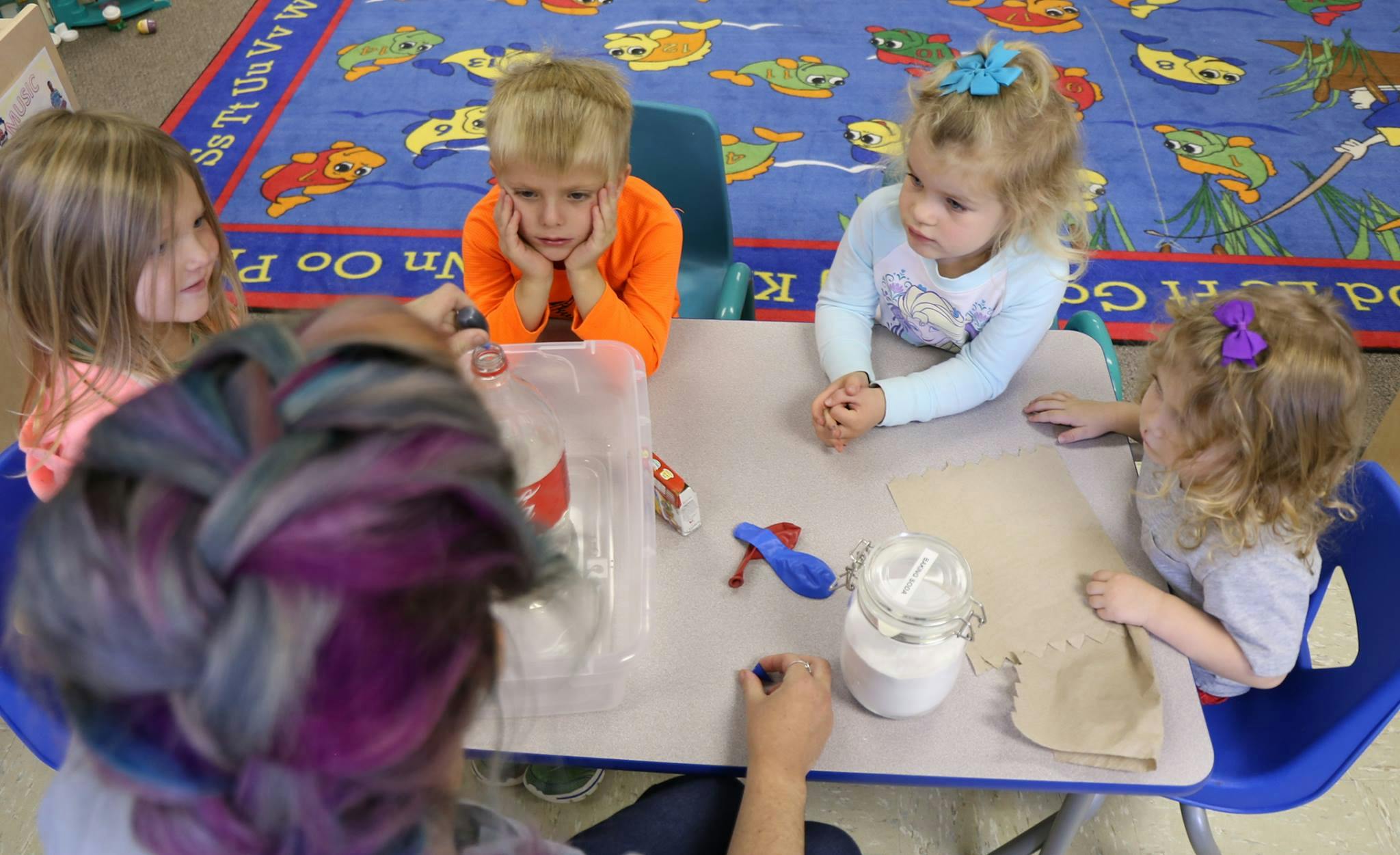 Children and an adult at a table with craft supplies