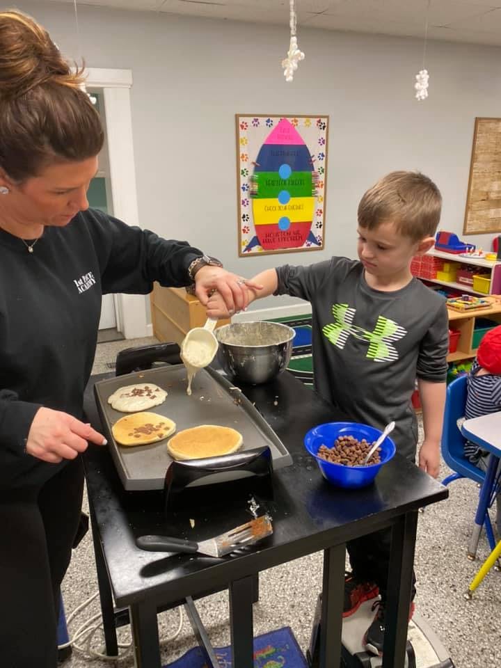 Person and child making pancakes on a griddle