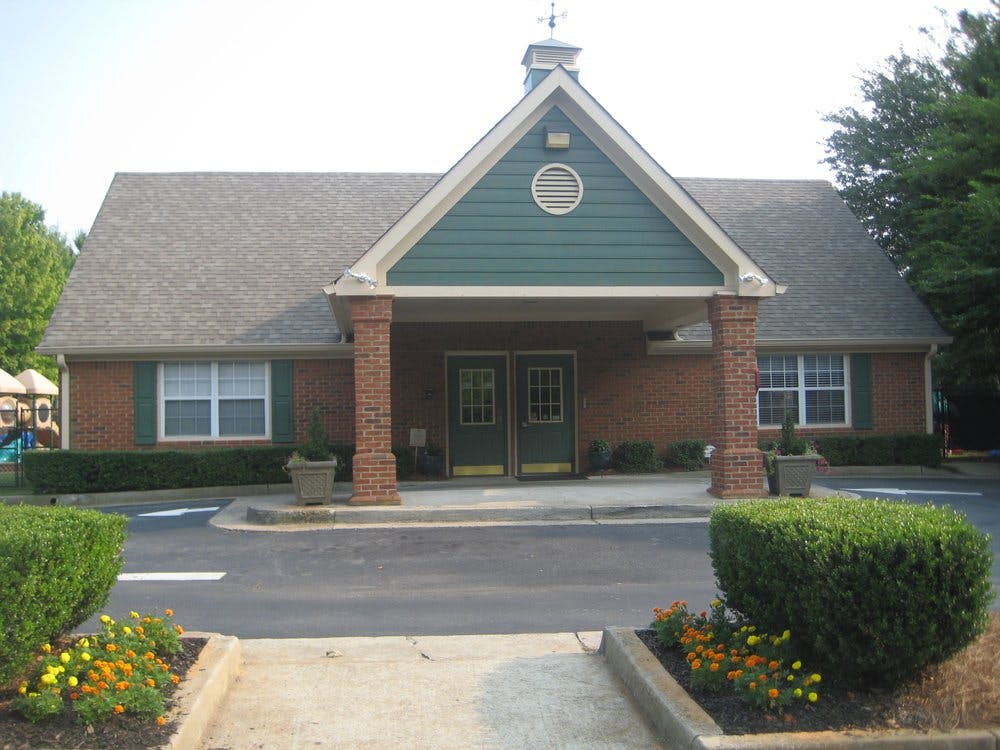 Front exterior of a brick building with a green gable and covered entrance