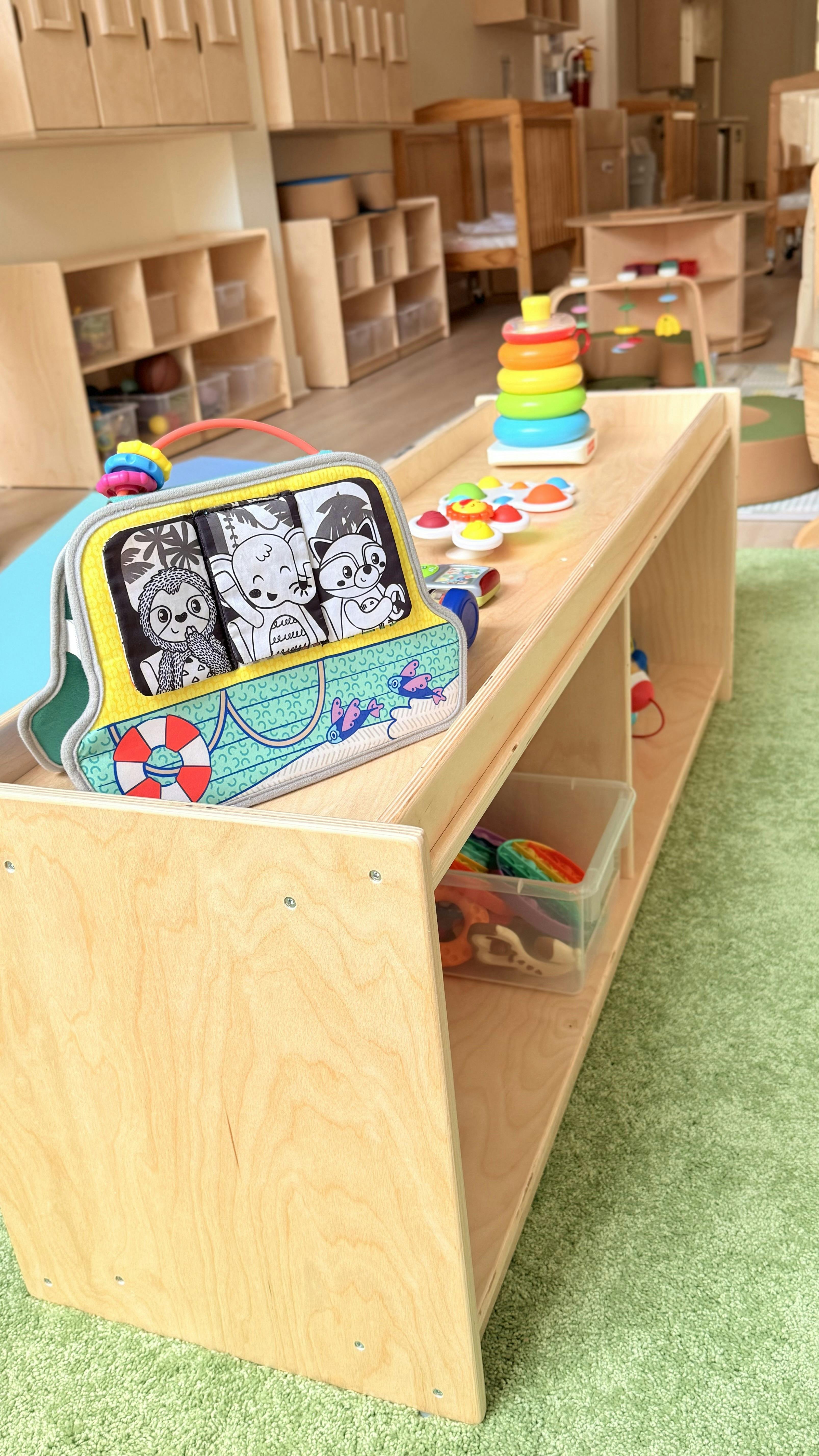 Toy bus with animal characters and a stacking ring toy on a wooden shelf