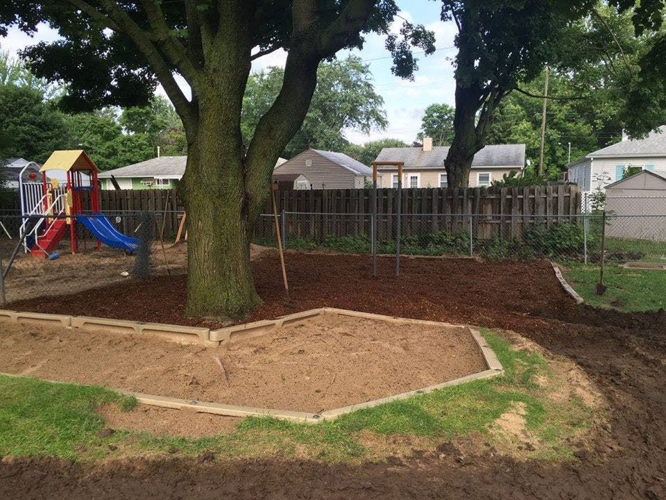 Backyard with a tree, playground equipment, and a sandbox