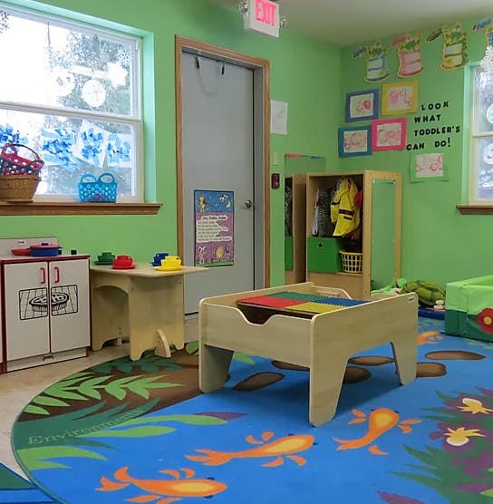 Playroom with colorful rug, small table, and toy kitchen