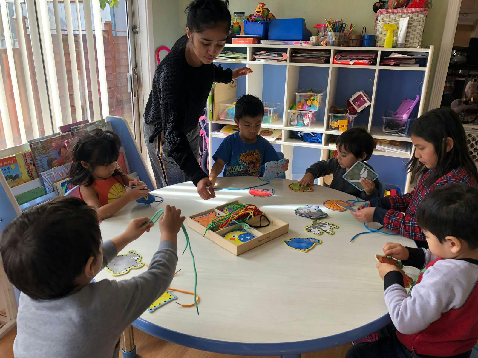 Adults and children gathered around a table with crafts and playing with toys