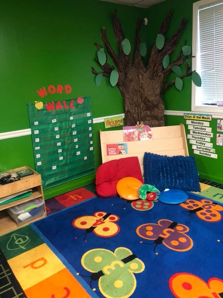 Classroom with a word wall, tree decoration, and butterfly rug