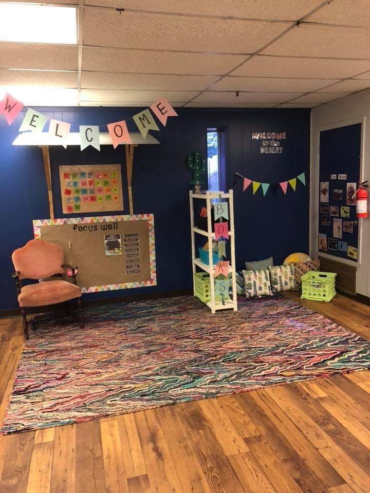 Classroom with a colorful rug, bulletin board, and welcome banner