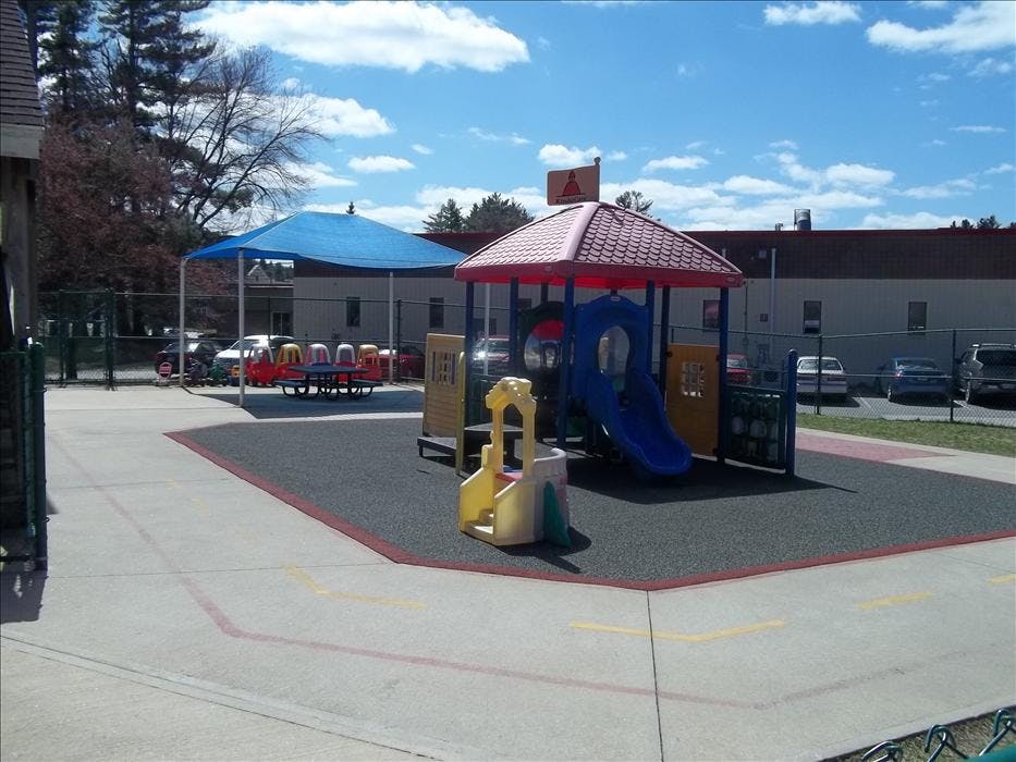 A playground with a small slide structure and a blue canopy over a picnic table