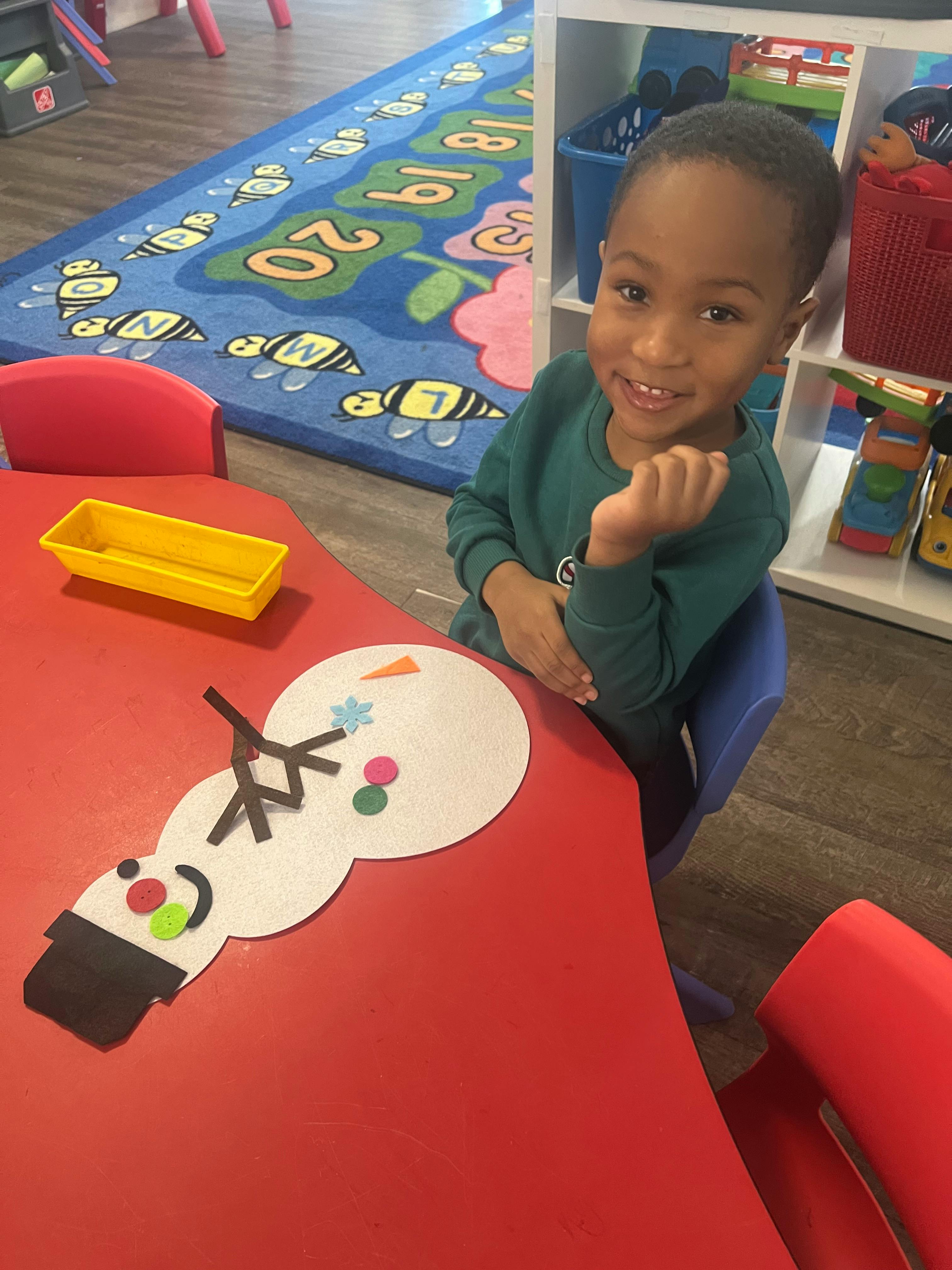Child sitting at a table with a snowman craft