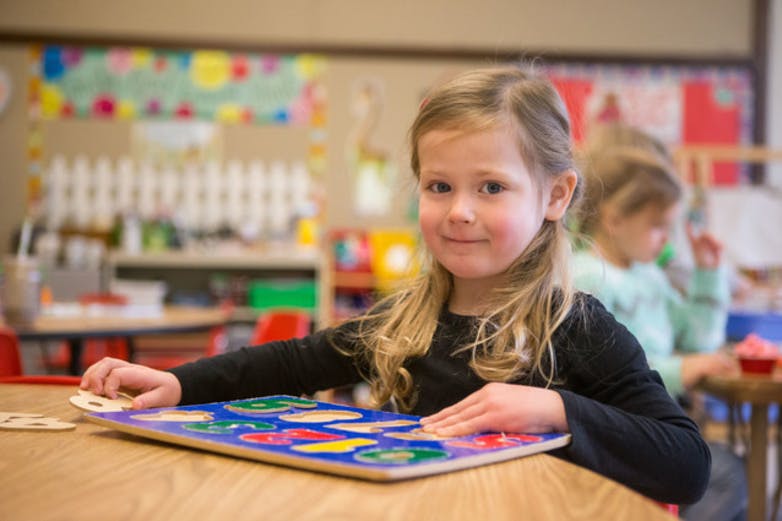 Child playing with a colorful puzzle in a classroom