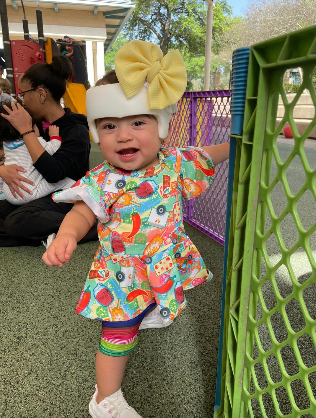 Child wearing a helmet with a bow and a patterned dress