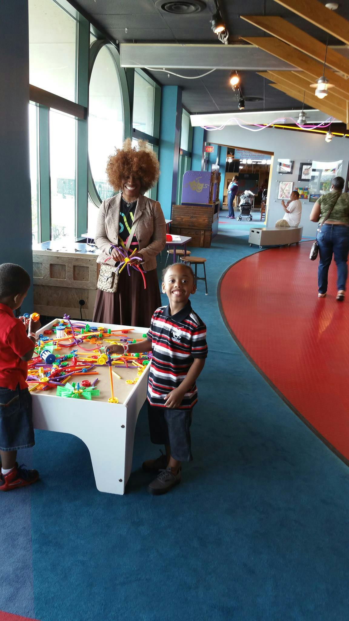 Adult and two children playing with colorful building toys at a table