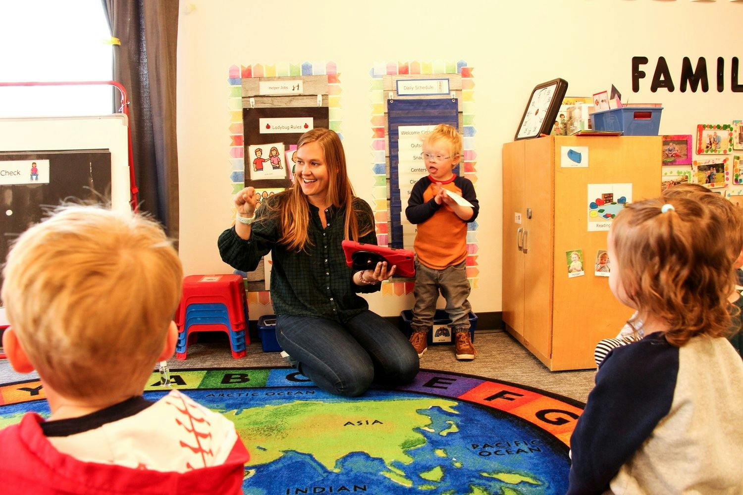 Person kneeling with children in a classroom