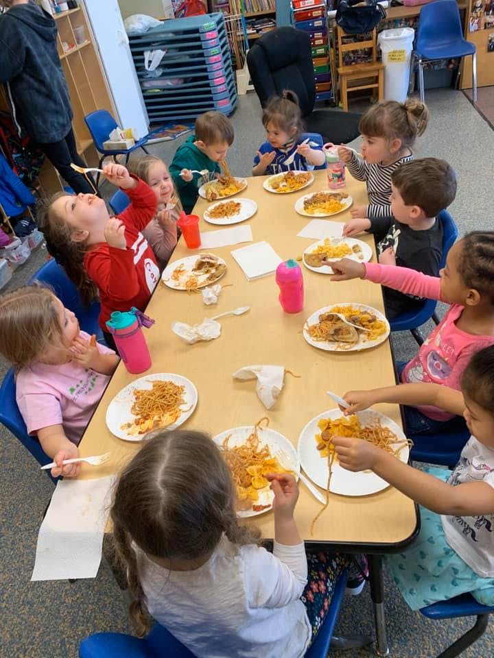 Children eating at a table in a classroom