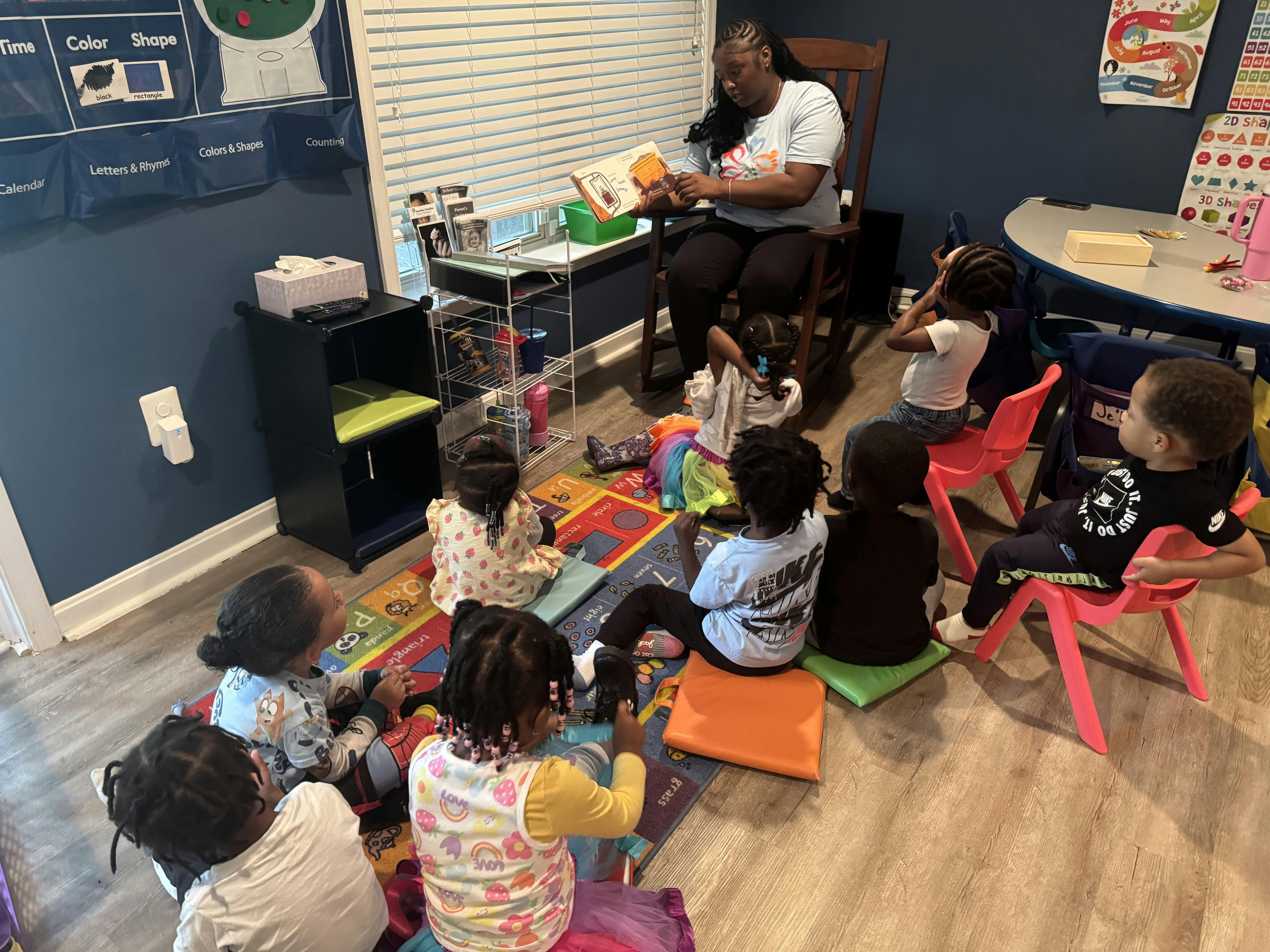 Person reading a book to a group of children in a classroom