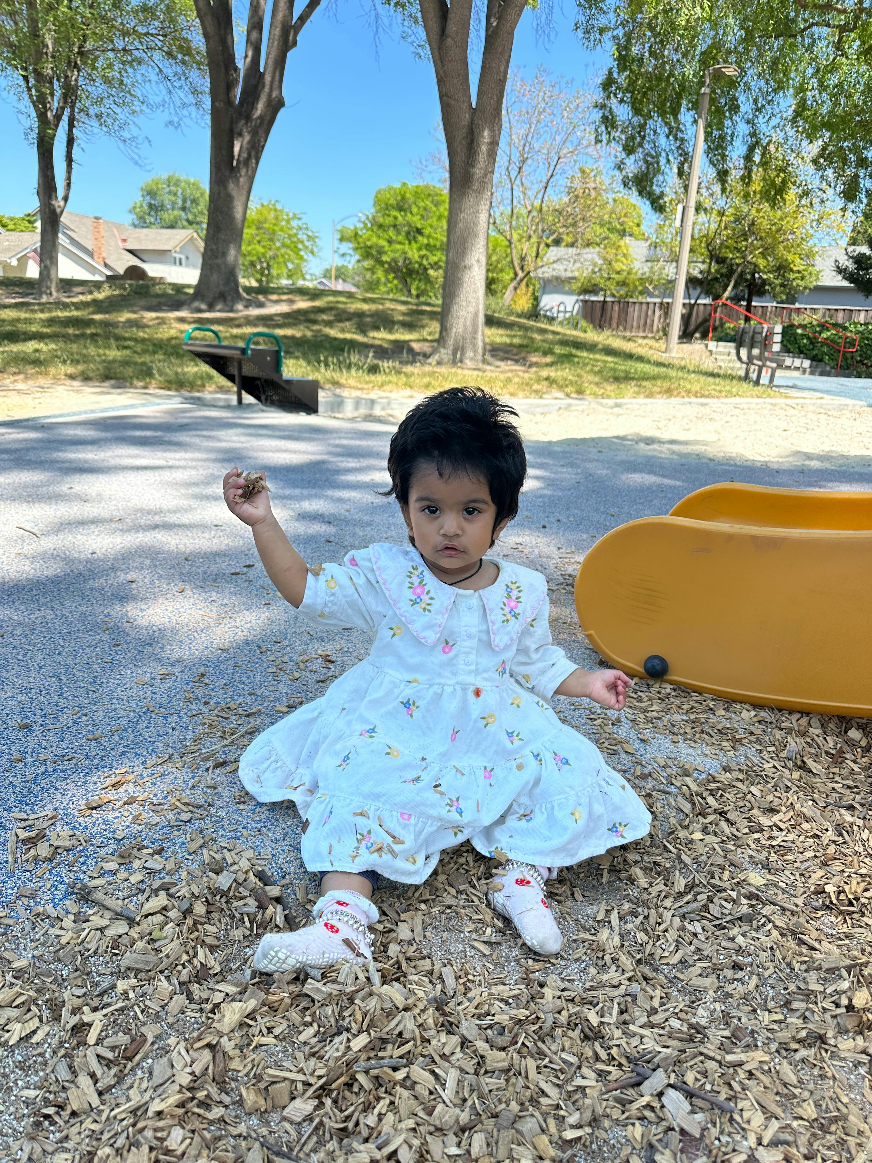 Child sitting on wood chips in a playground