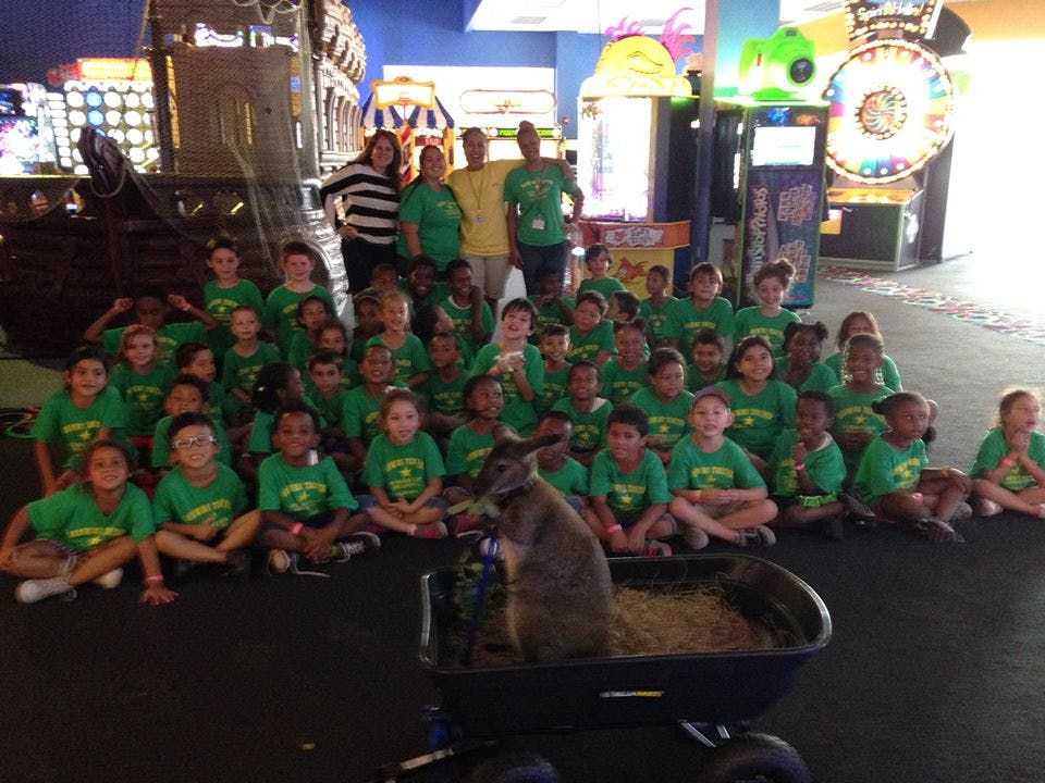Group of adults and children in green shirts posing with an animal