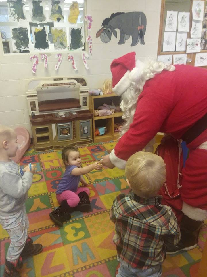 Person dressed as Santa Claus interacting with children in a classroom