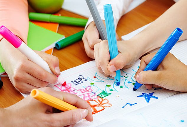 Multiple people drawing on paper with colorful markers