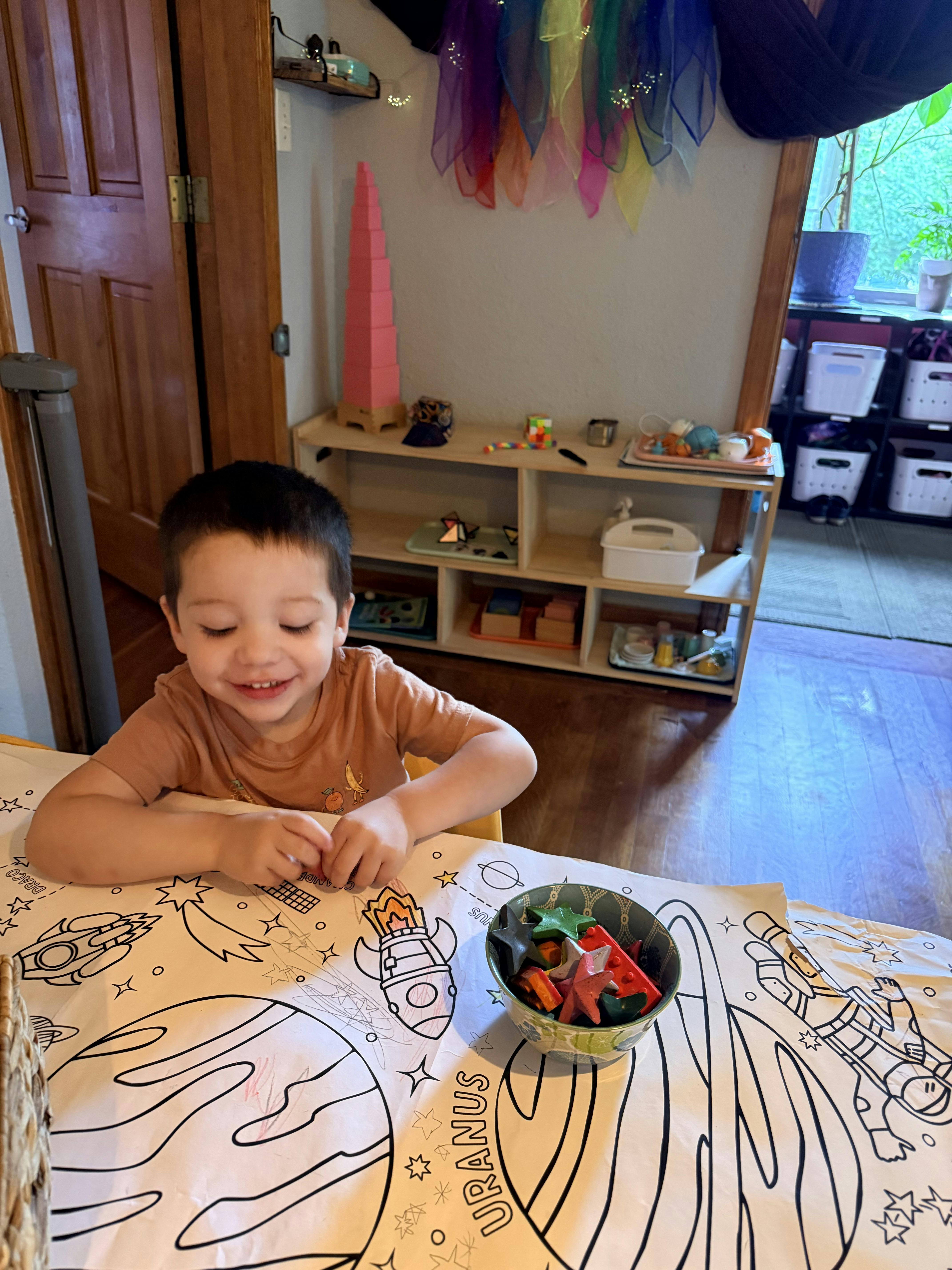 Child coloring at a table with space-themed decorations
