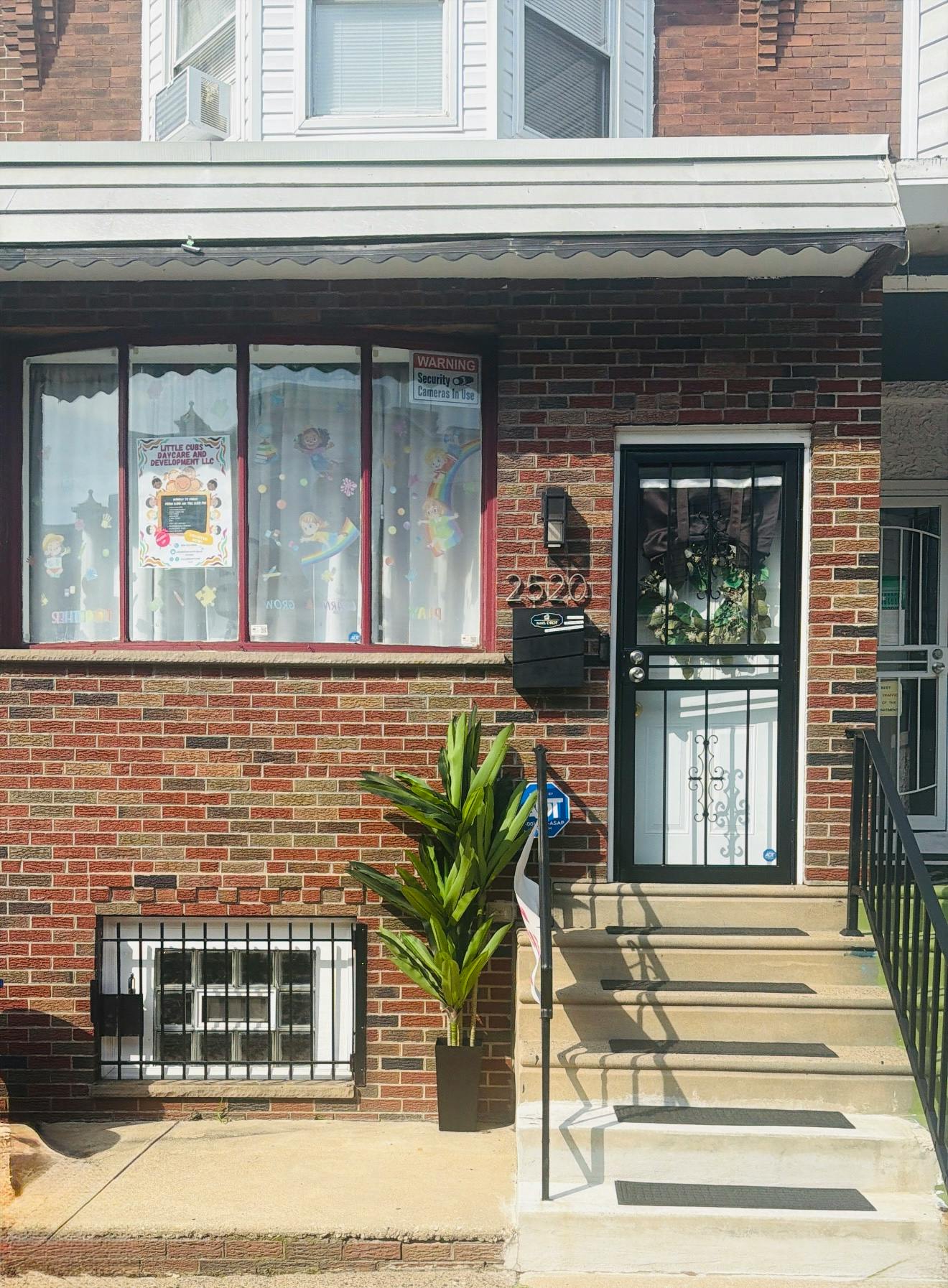 Brick house exterior with daycare signage in the window and entry steps