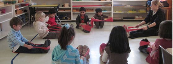 Adult and children sitting on floor in classroom