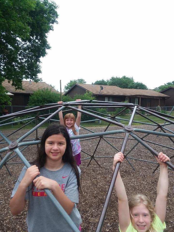 Three children on a playground dome climber