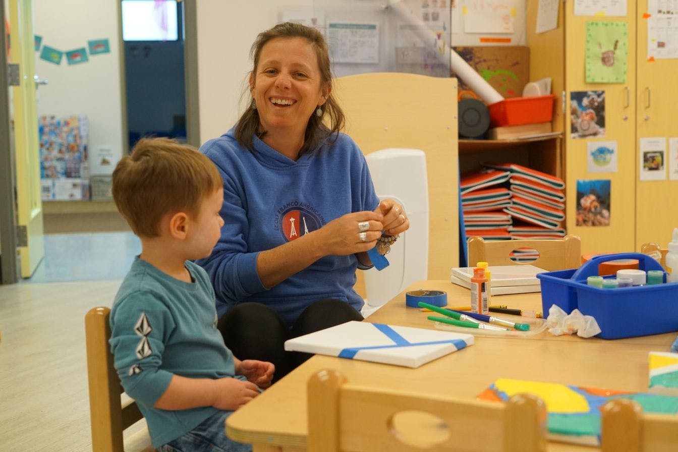 Person and child painting in a classroom