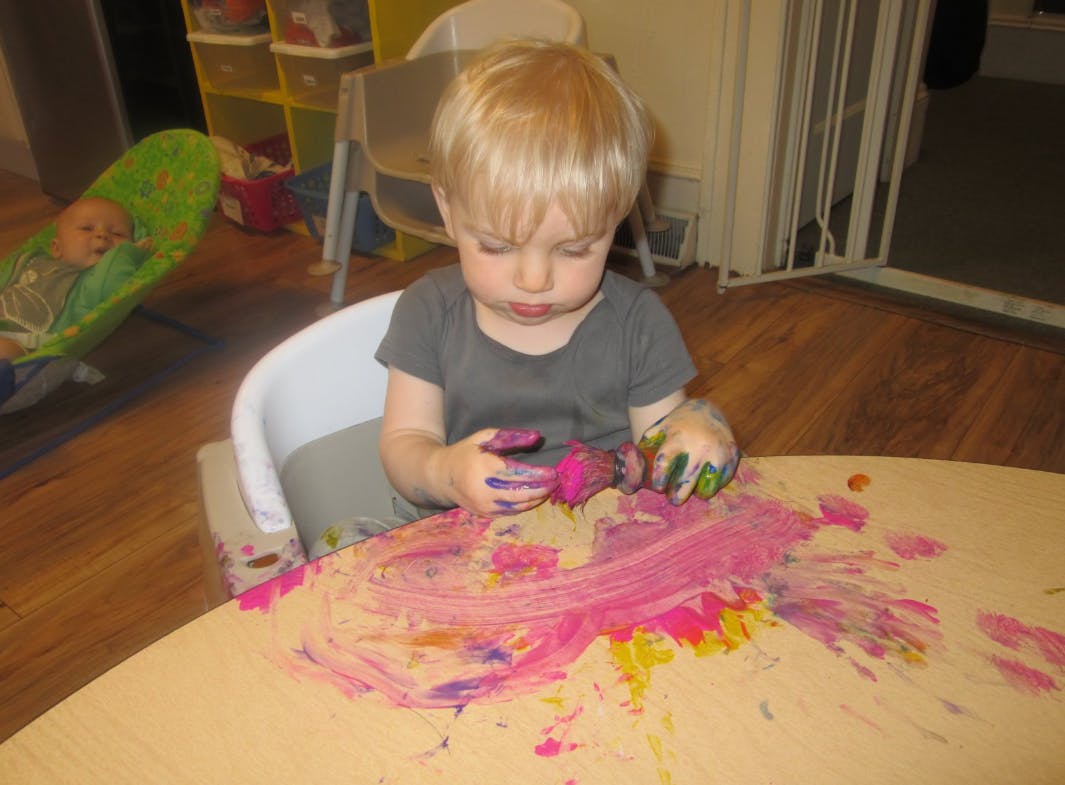 Child finger painting at a table