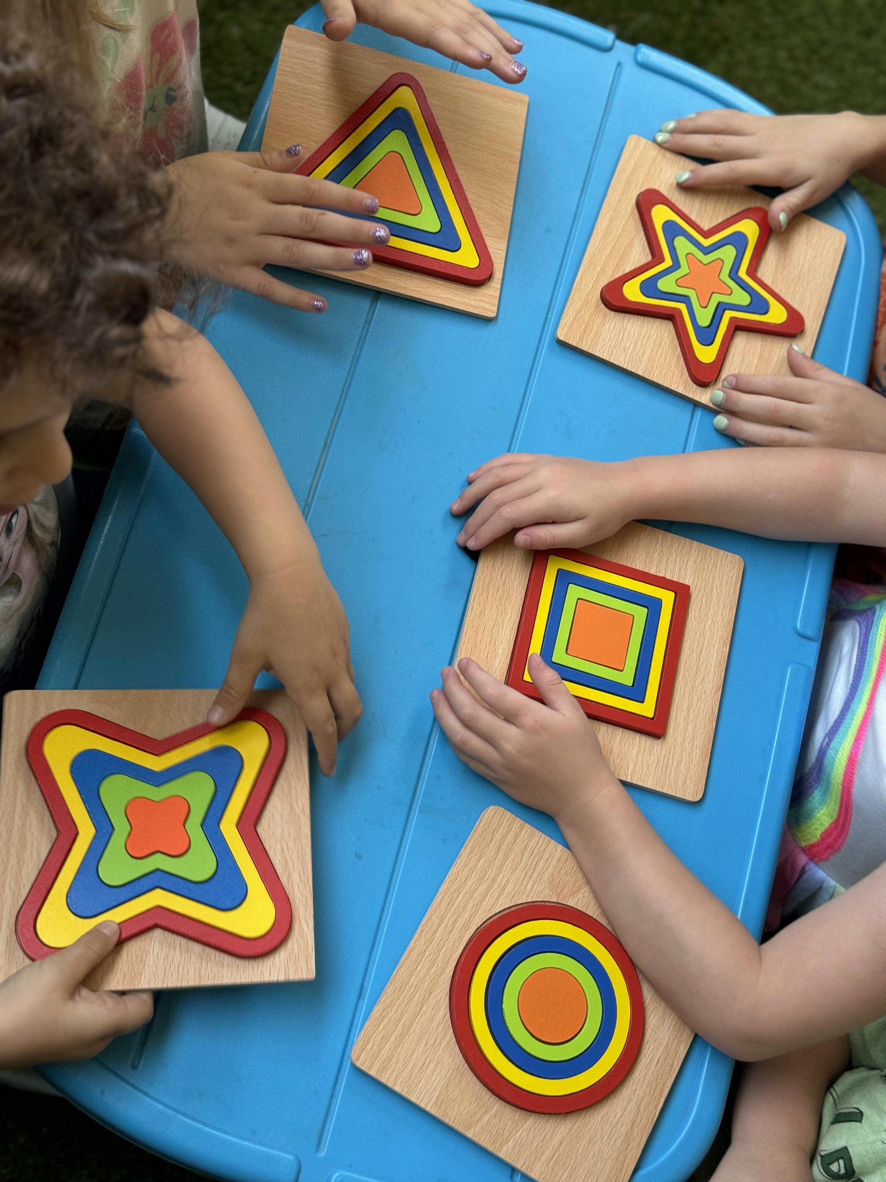 Children's hands playing with colorful shape puzzles on a blue table