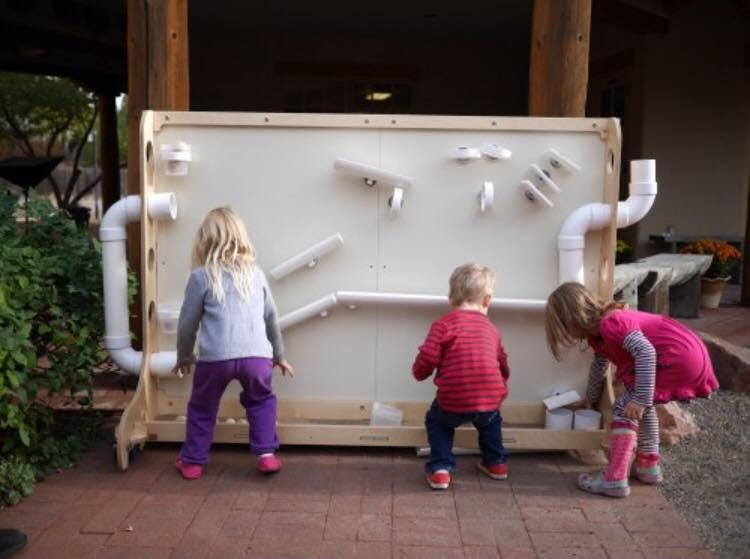 Three children playing with a water wall