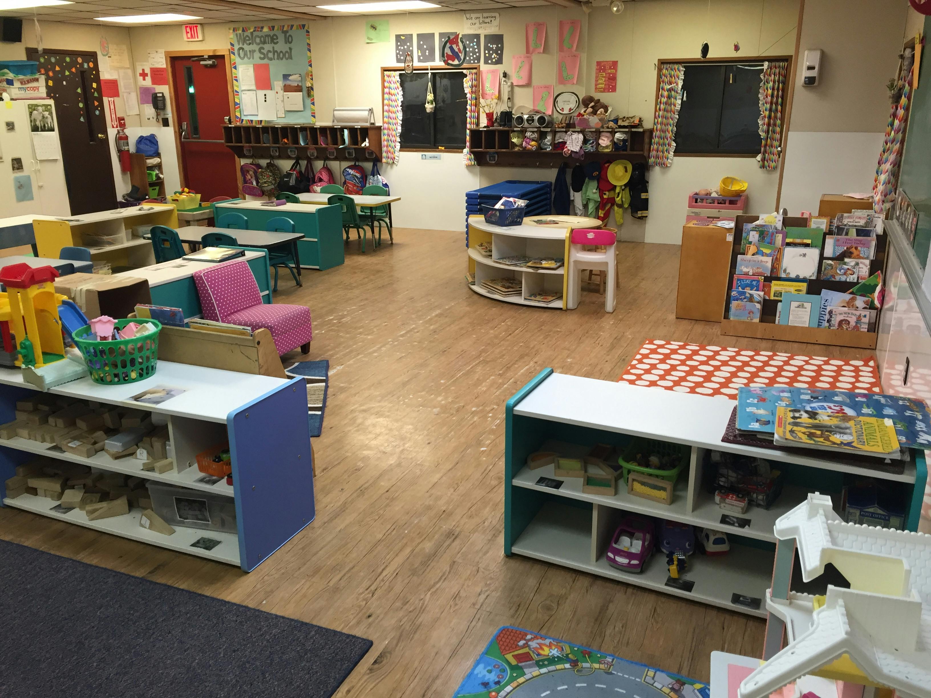 Empty classroom with tables, chairs, and shelves of toys