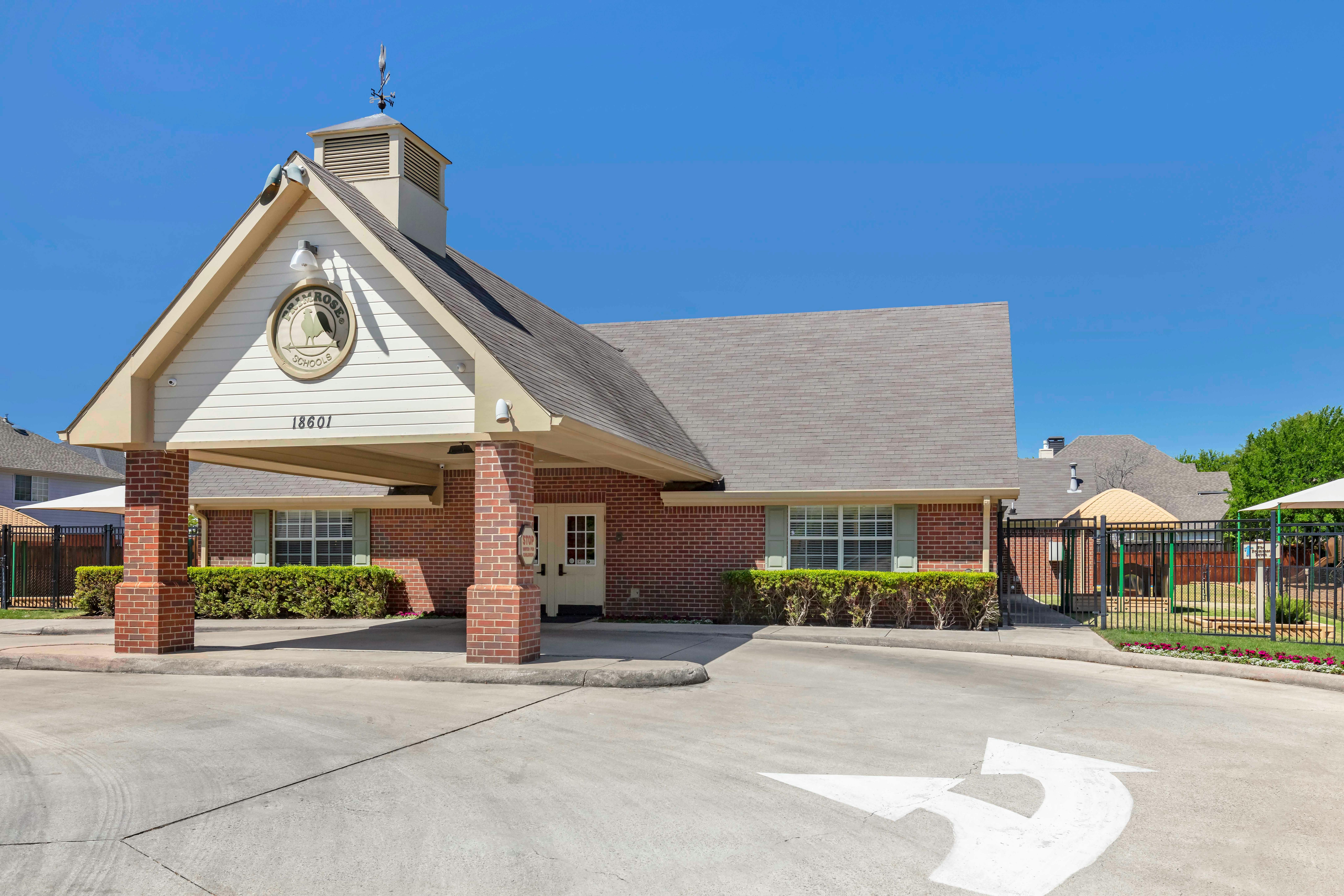 A brick building with an extended awning over a driveway, with a playground visible
