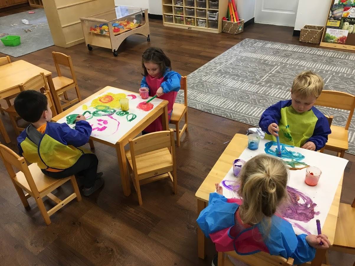 Children painting at tables in a classroom