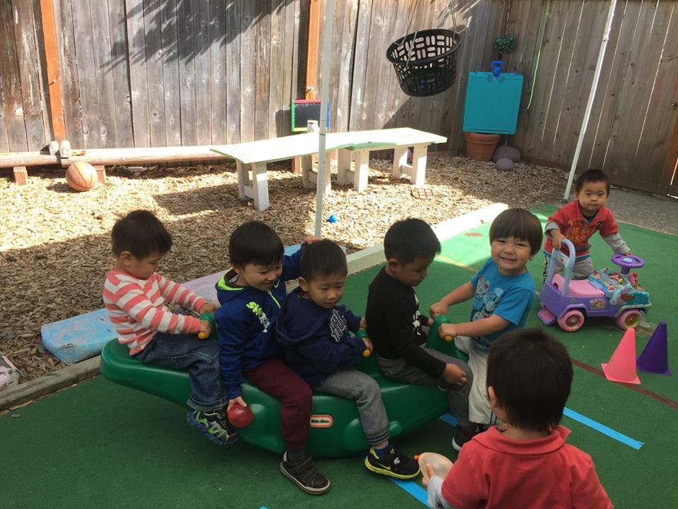 Children playing on a seesaw and with toys in a play area