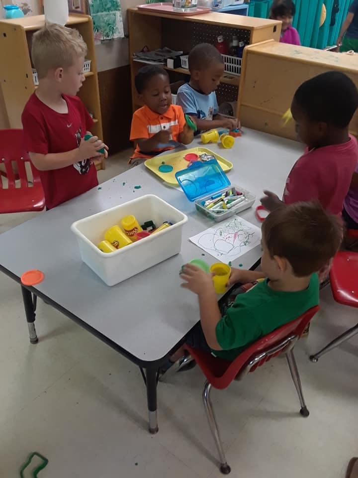 Children playing with toys at a table in a classroom