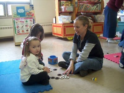 Adult and two children sitting on floor playing with game pieces