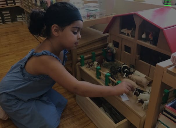 Child playing with a toy barn and animal figures