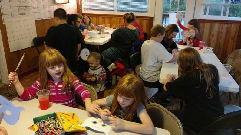 Children and adults gathered around tables, some crafting