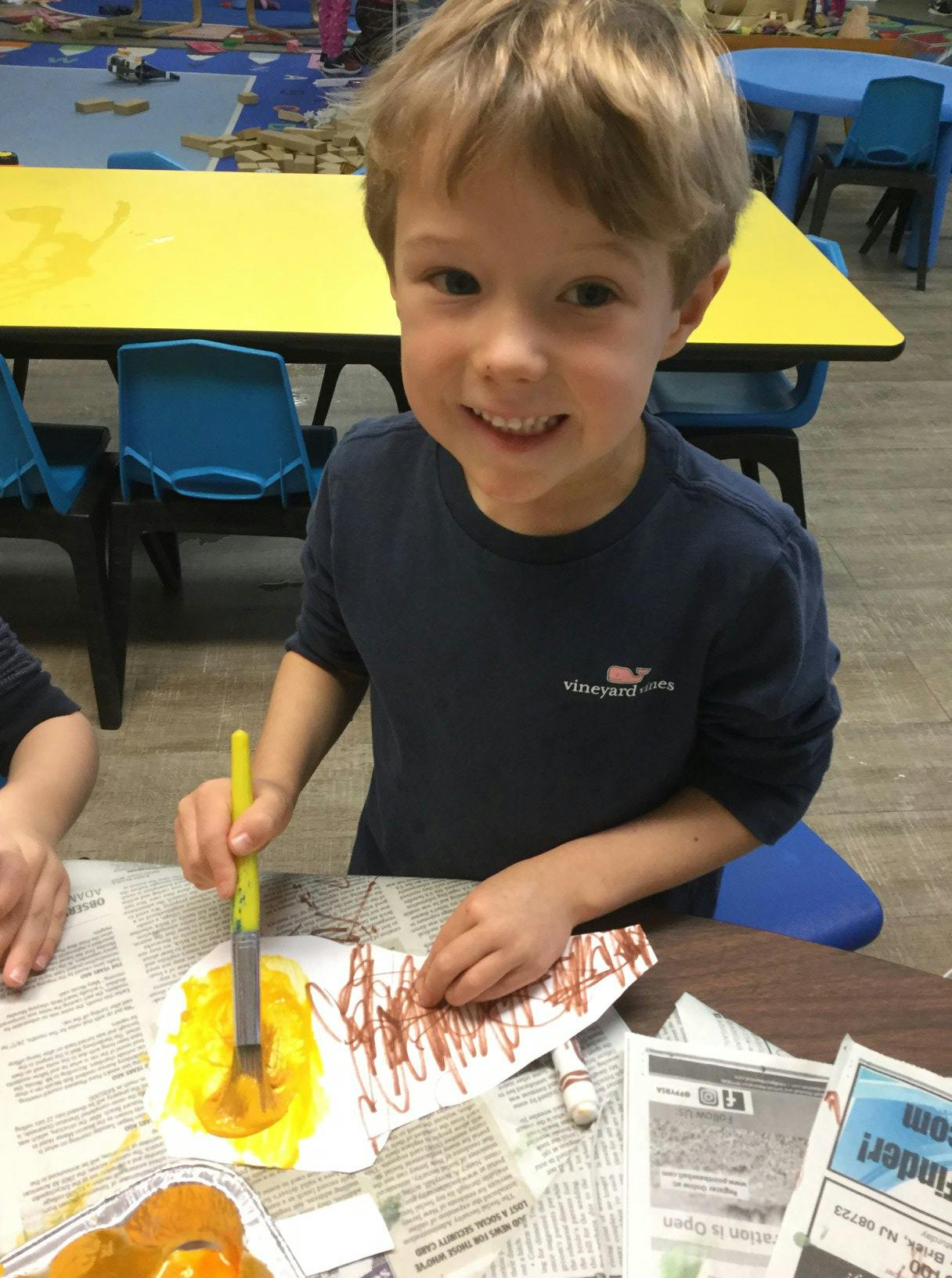 Child painting a paper cutout at a table