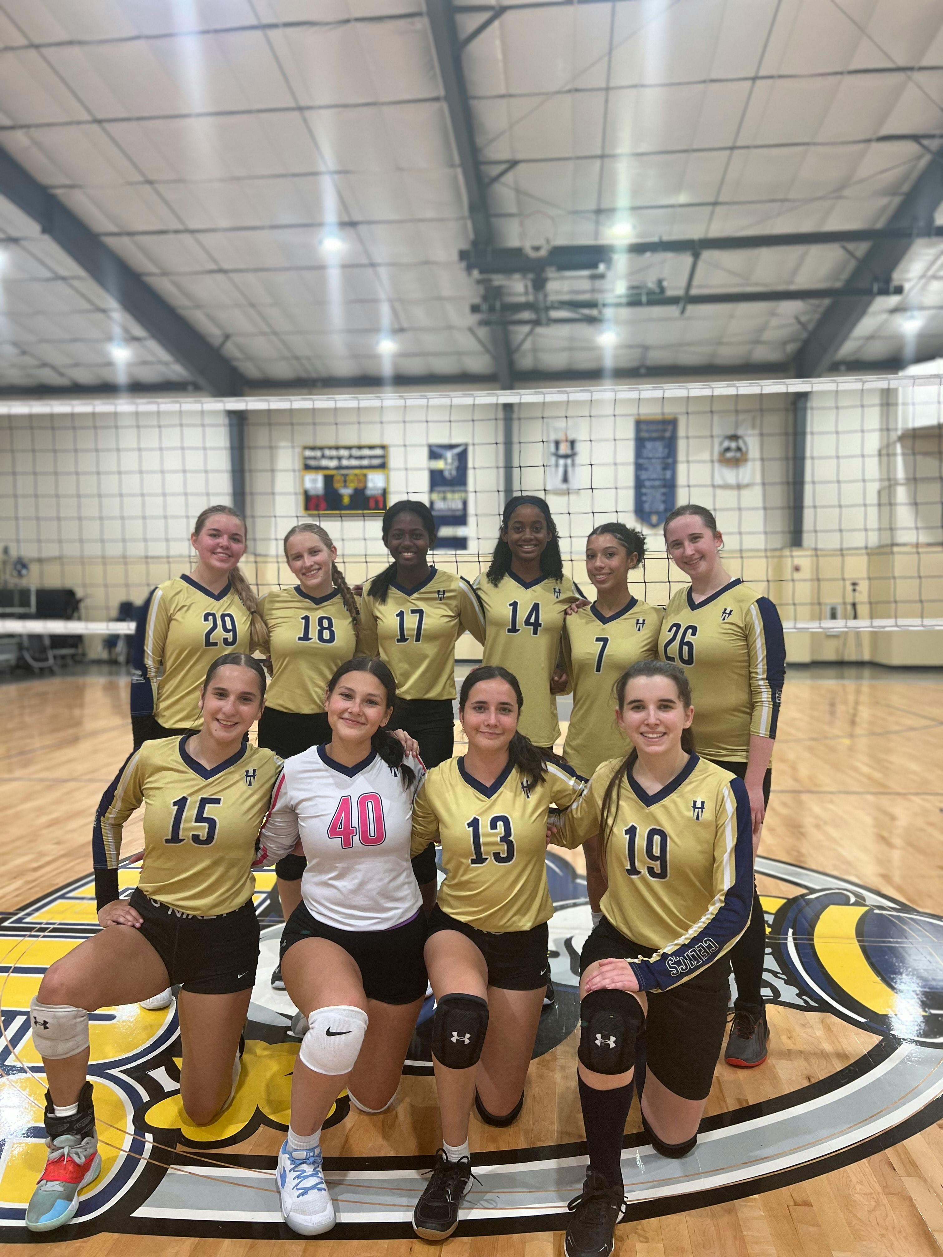A volleyball team of ten children in gold and black uniforms
