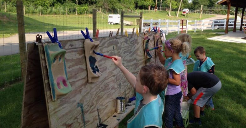 Children painting on an outdoor easel
