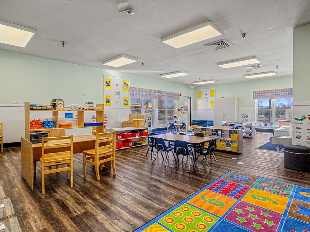 Empty classroom with tables, chairs, and learning materials