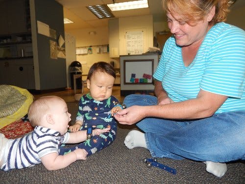 Adult and two children on floor playing with small object