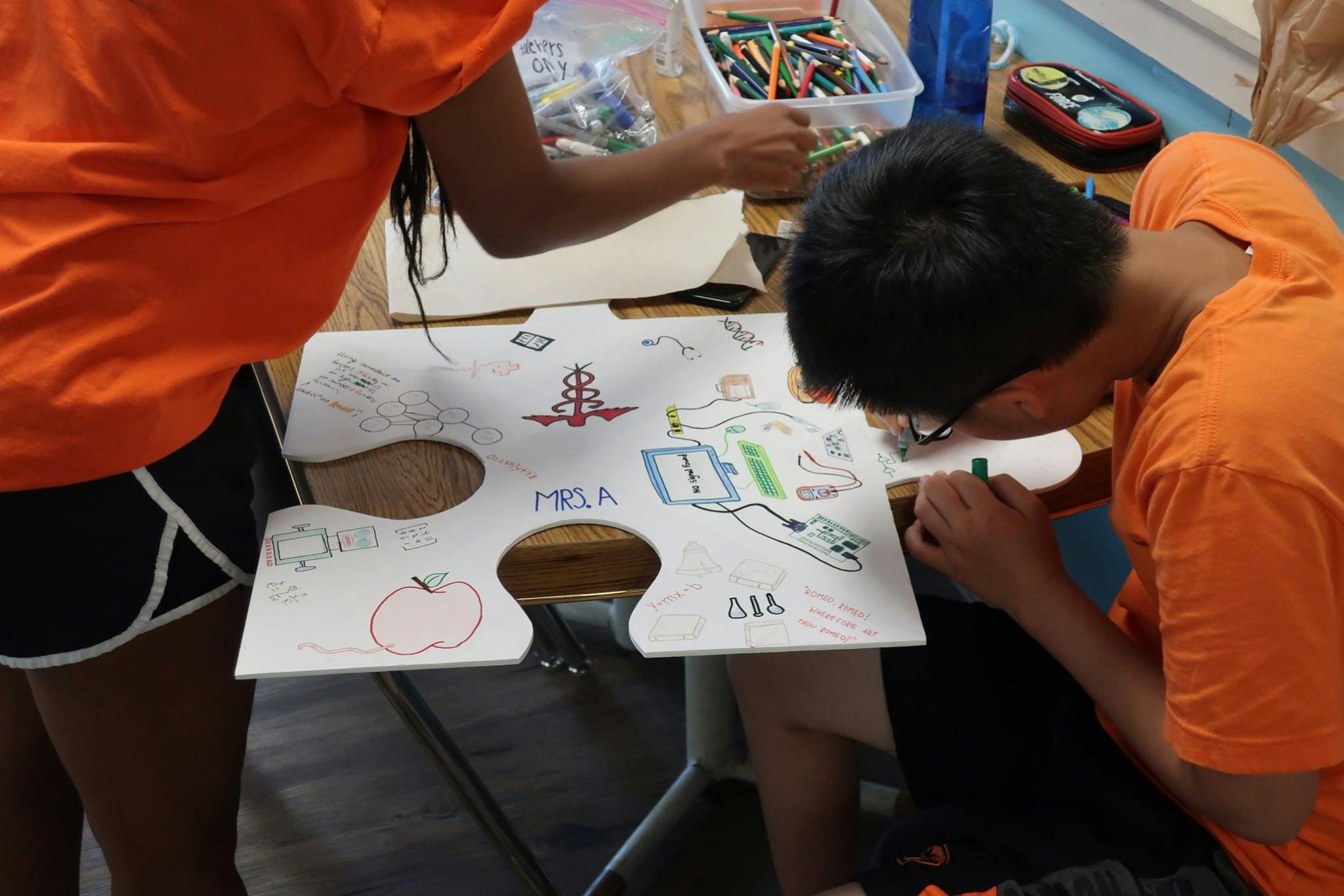 Two people drawing on a large puzzle piece