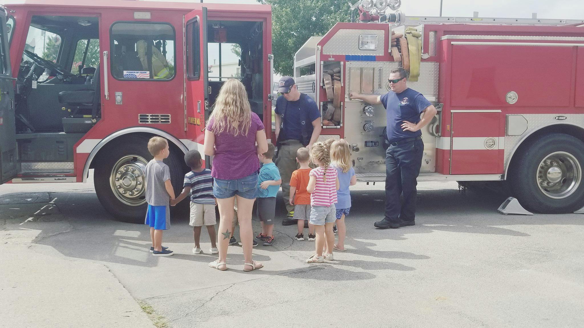 Adults and children gathered around fire trucks